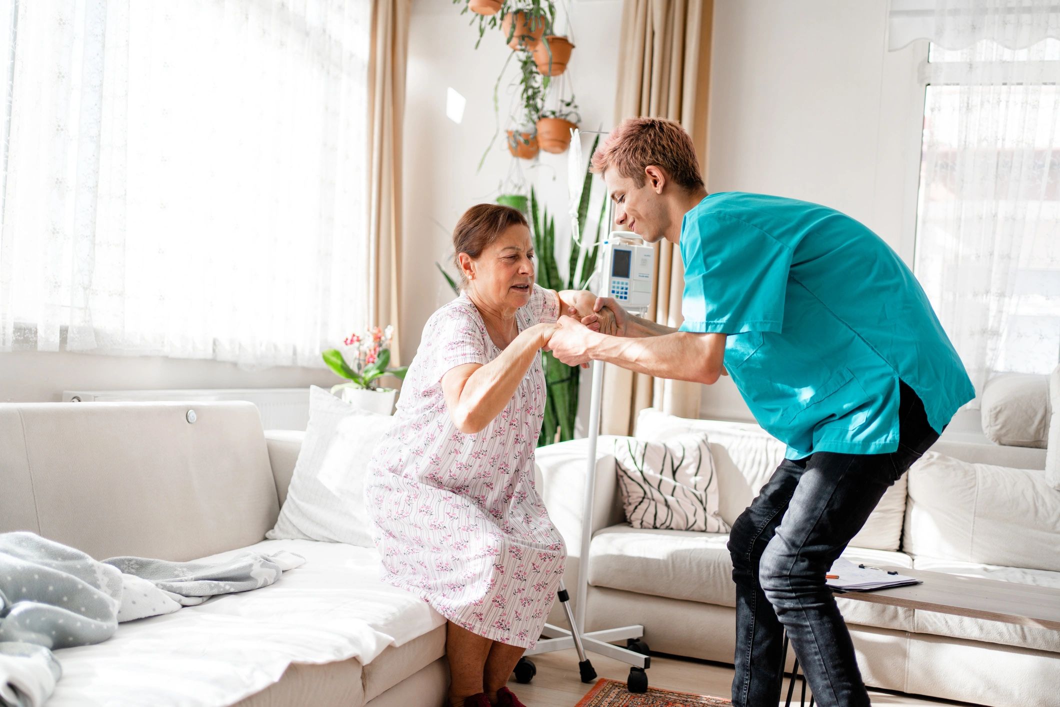 Healthcare worker helping a senior woman stand in her living room